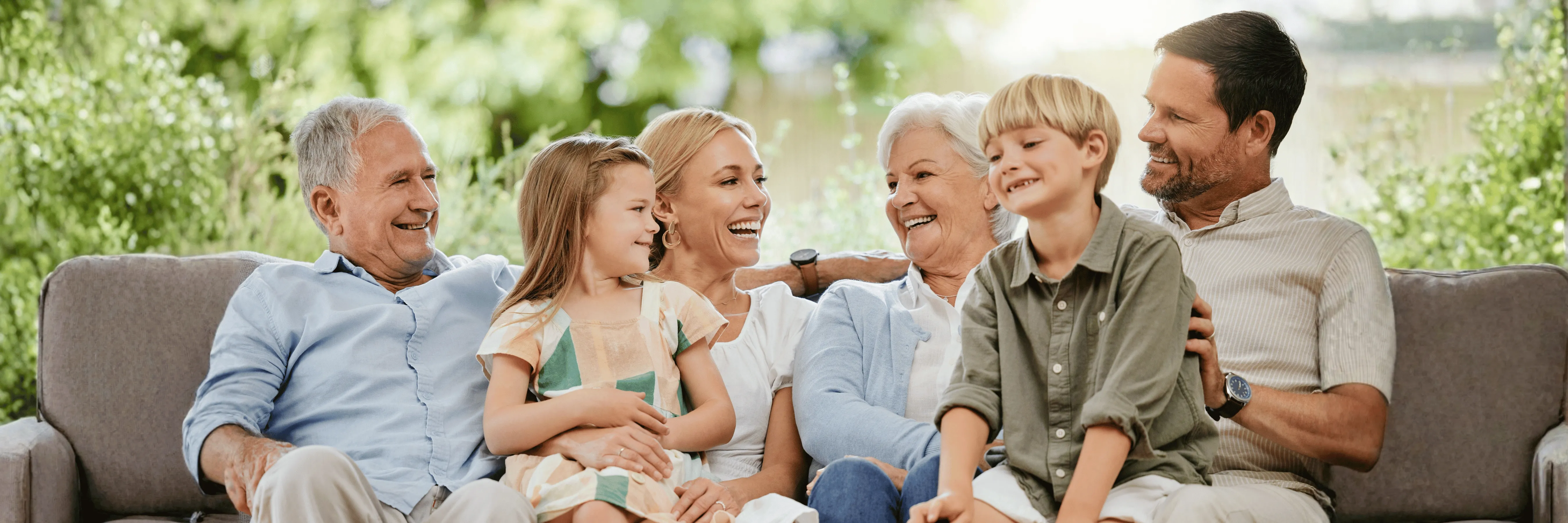 Multi-generational family laughing together on a couch outdoors